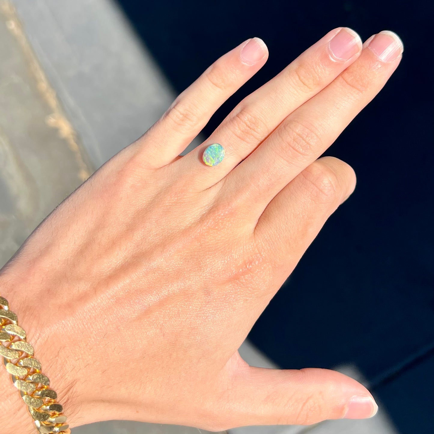 A loose, 1.26 carat semi-black opal stone from Lightning Ridge, Australia. The opal is green and blue.