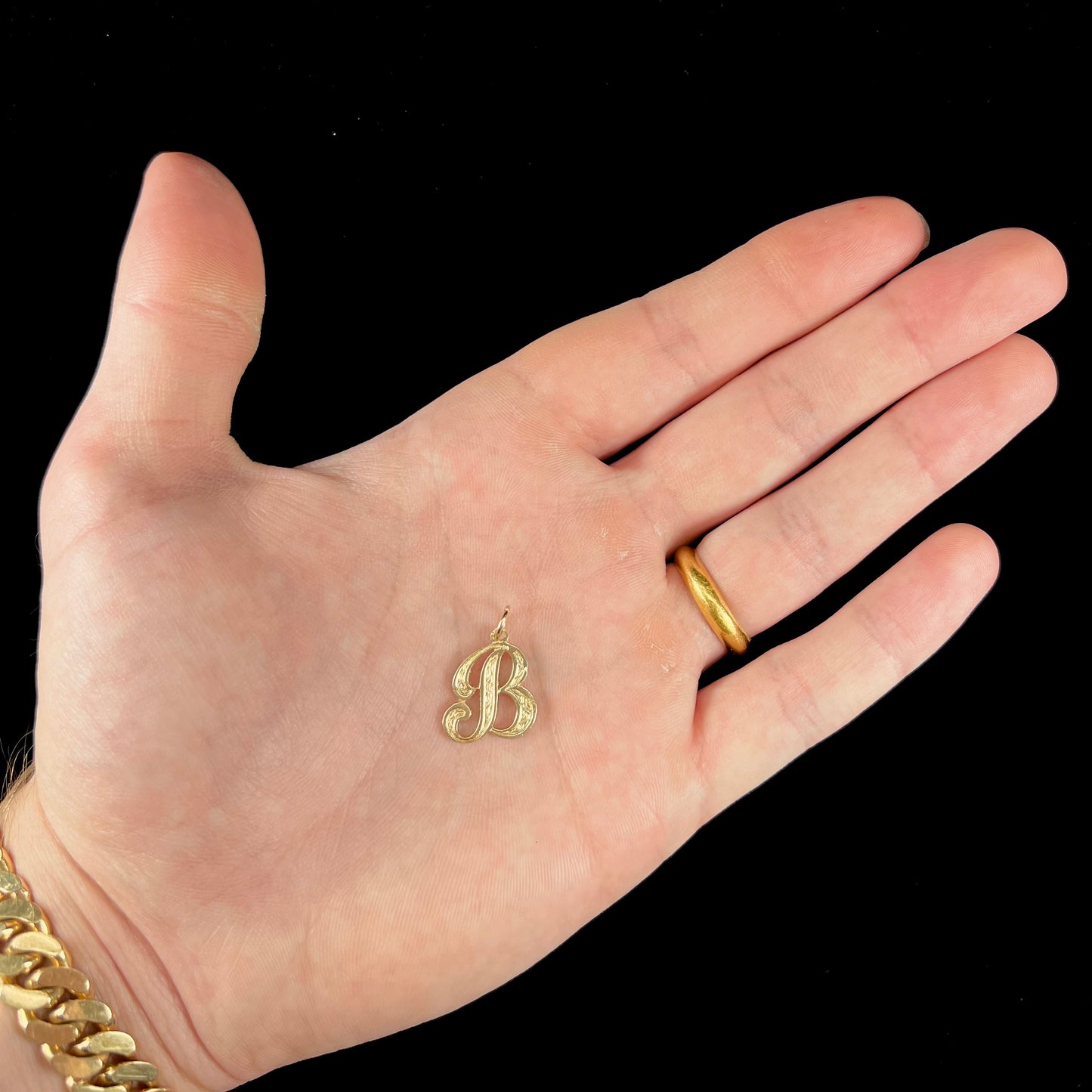 A 14 karat yellow gold stylized script letter "B" pendant, resembling the Barbie logo.