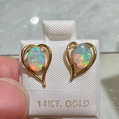 A pair of yellow gold, heart shaped stud earrings set with oval cabochon cut natural opal stones.