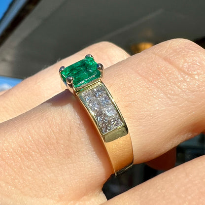 An 18 karat yellow gold ladies' emerald ring, channel set with princess cut diamonds.