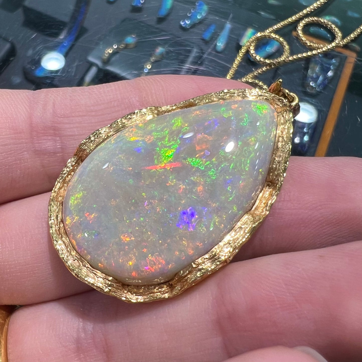 A ladies' natural, pear shaped, gray base Australian opal pendant set in 18 karat yellow gold.