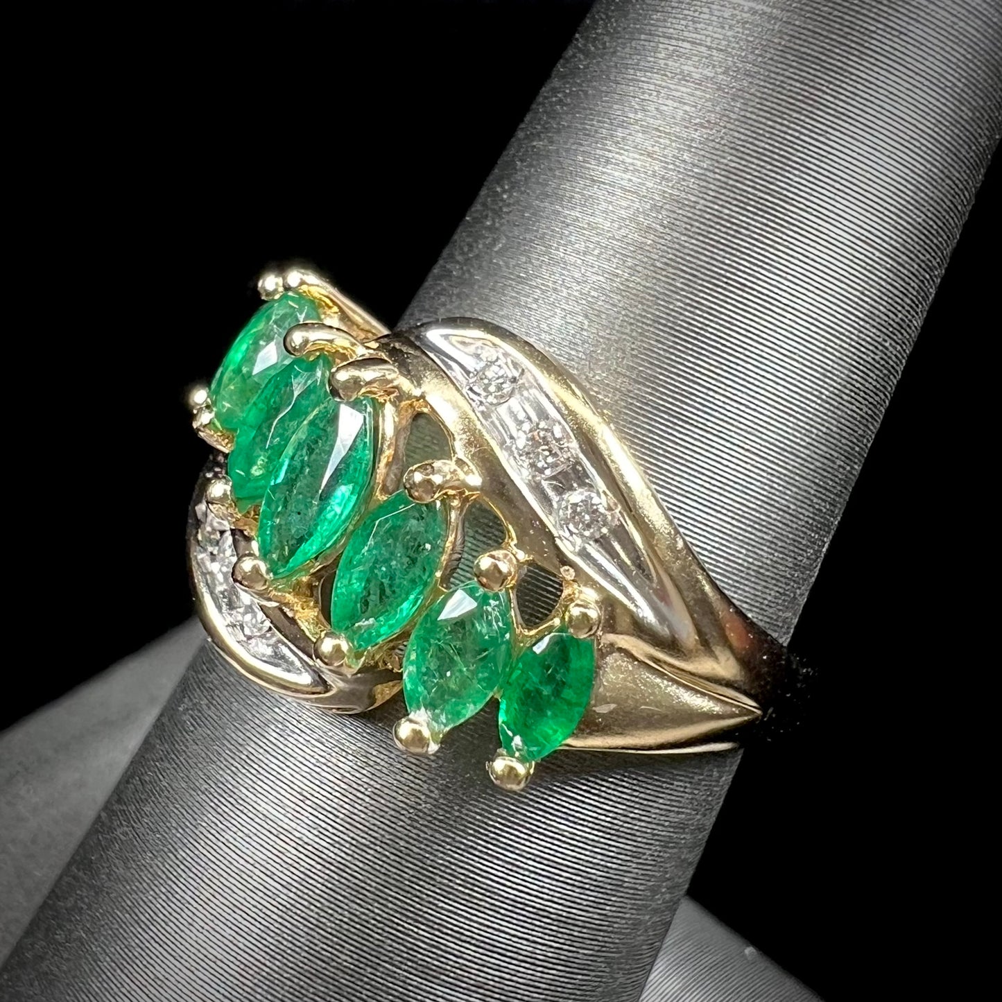 A vintage, 1970's style yellow gold ring set with marquise cut emeralds and round brilliant cut diamonds.