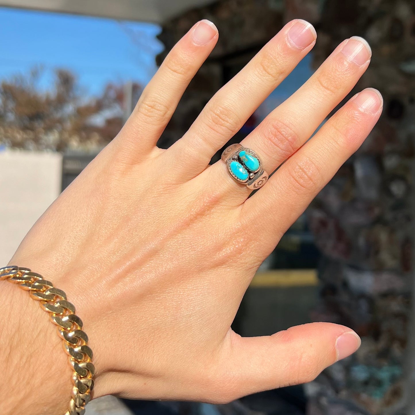 A unisex sterling silver ring bezel set with two Pilot Mountain turquoise stones.  The ring is stamped with sun patterns.