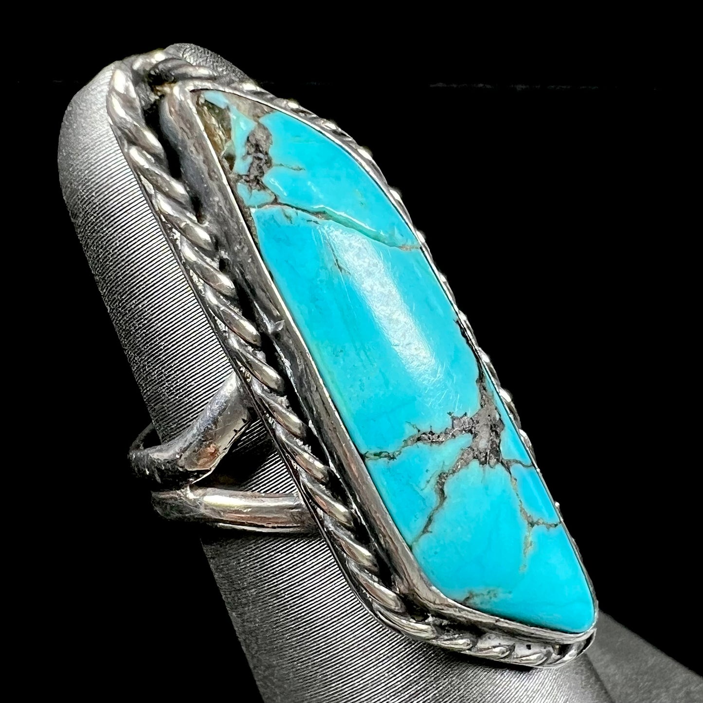 A vintage, Southwest style sterling silver ring set with a natural turquoise stone. The stone is blue with a black matrix.