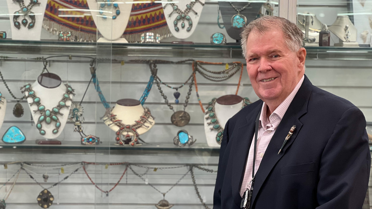 George Goodman, Certified Gemologist, standing in front of Native American squash blossom necklaces at Burton's Gems and Opals.
