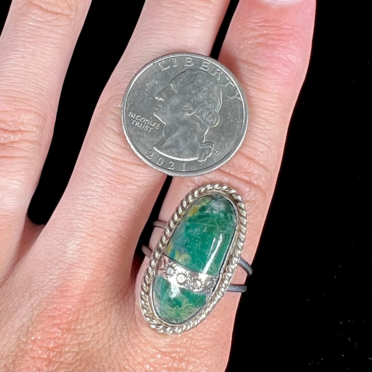 A green agate solitaire ring handmade from sterling silver. There is a stamped pattern of suns across a strip of metal over the stone.