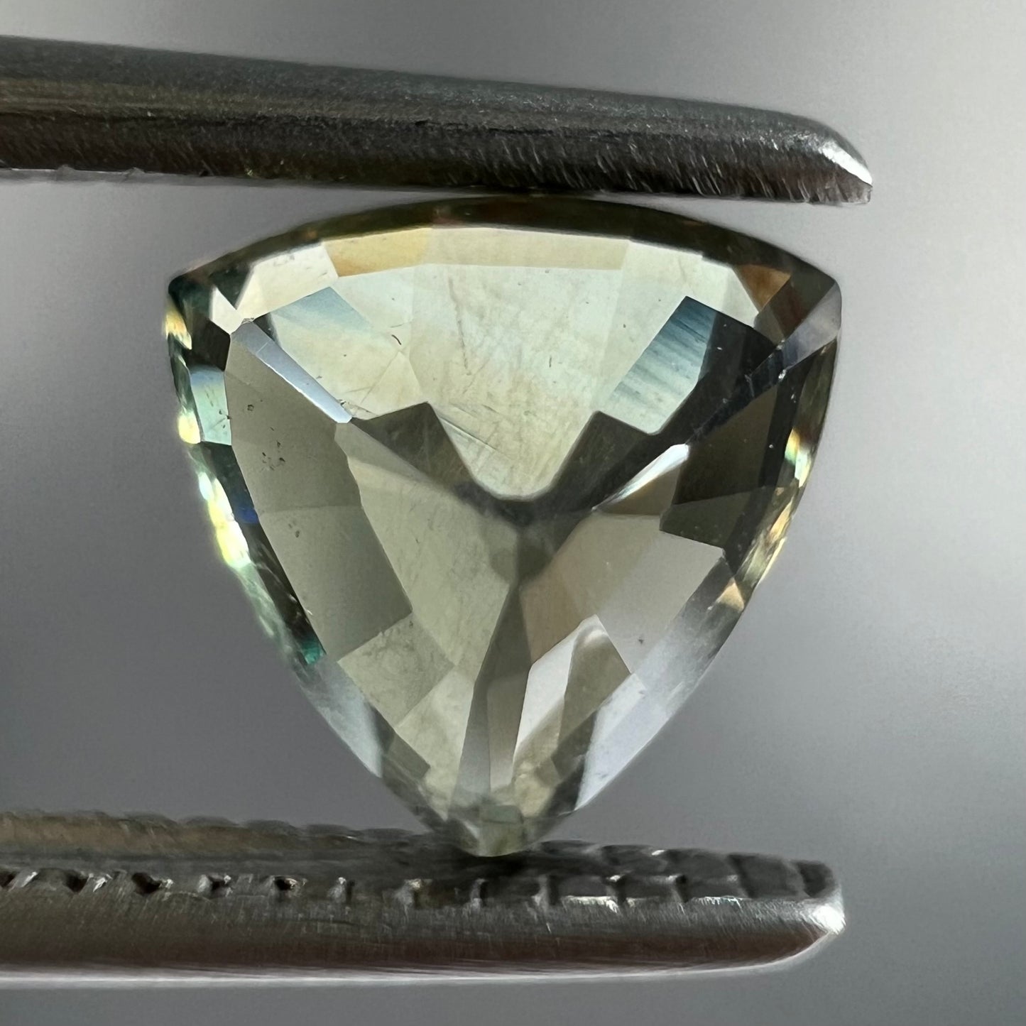 A natural, 1.10 carat, trillion cut alexandrite gemstone. The stone changes colors from dark olive green to faint purplish green.