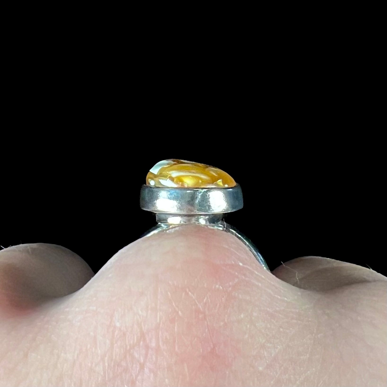 An adjustable sterling silver solitaire ring set with a cabochon cut butterscotch amber stone.