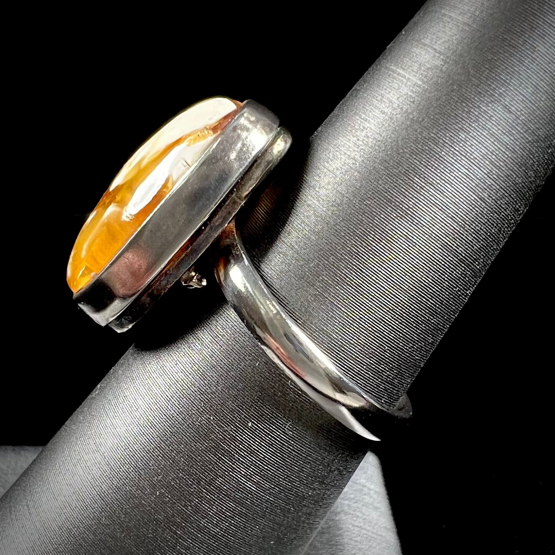 An adjustable sterling silver solitaire ring set with a cabochon cut butterscotch amber stone.