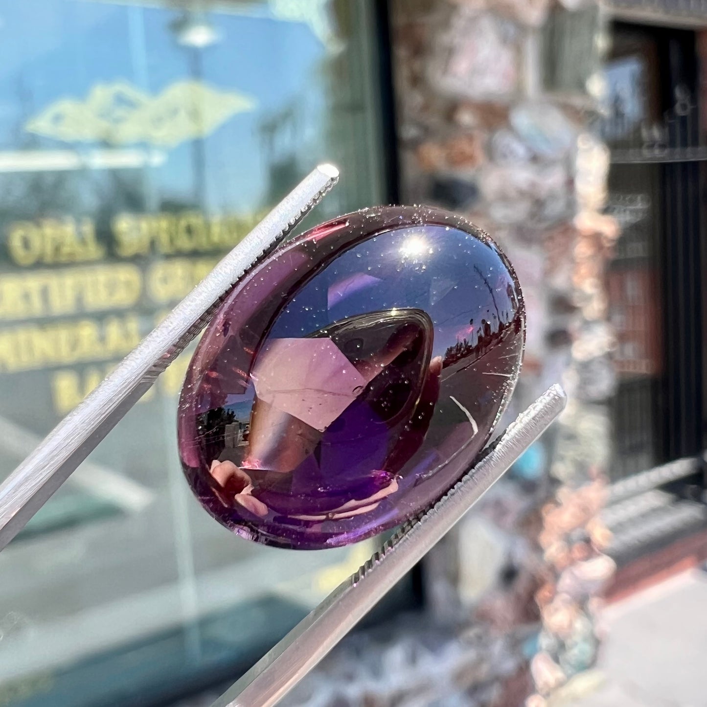 A loose, oval buff top cut amethyst gemstone. The top of the stone is domed, and the bottom is faceted.