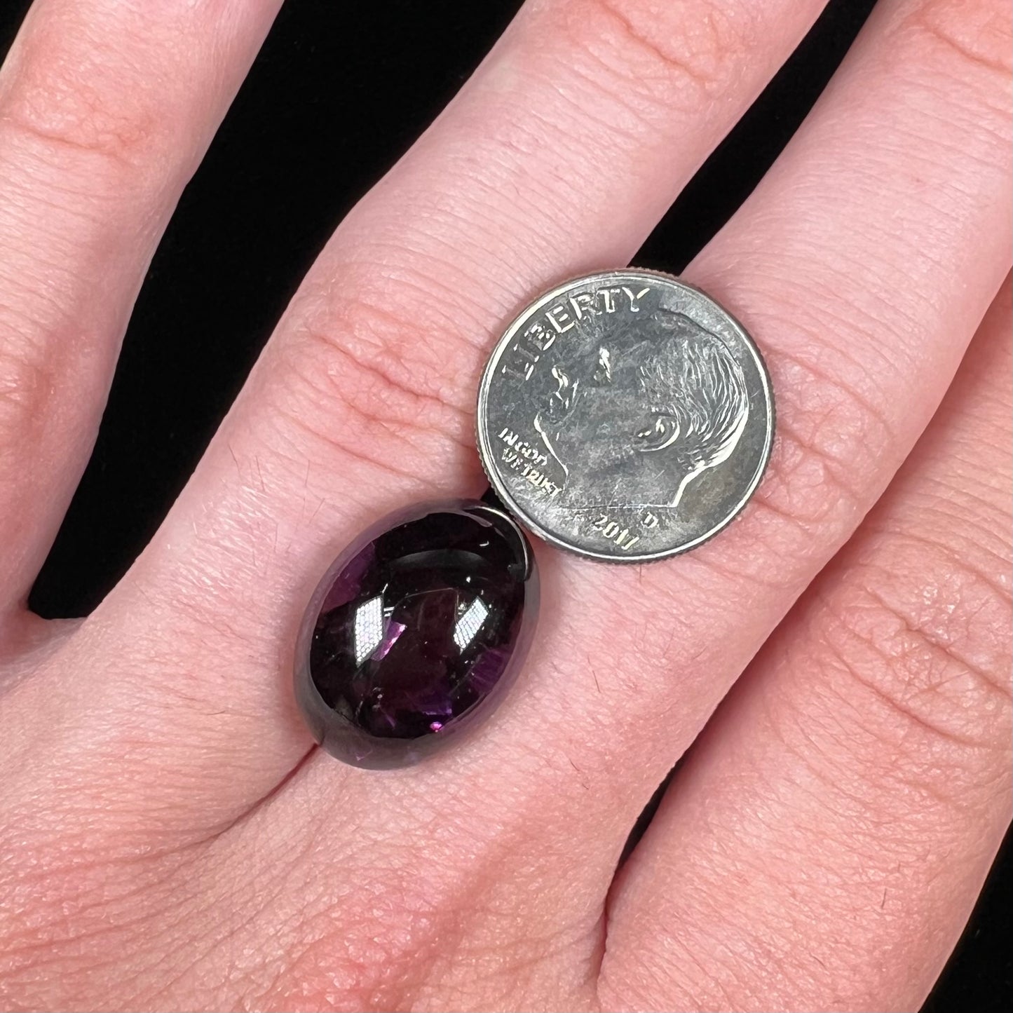 A loose, oval buff top cut amethyst gemstone. The top of the stone is domed, and the bottom is faceted.