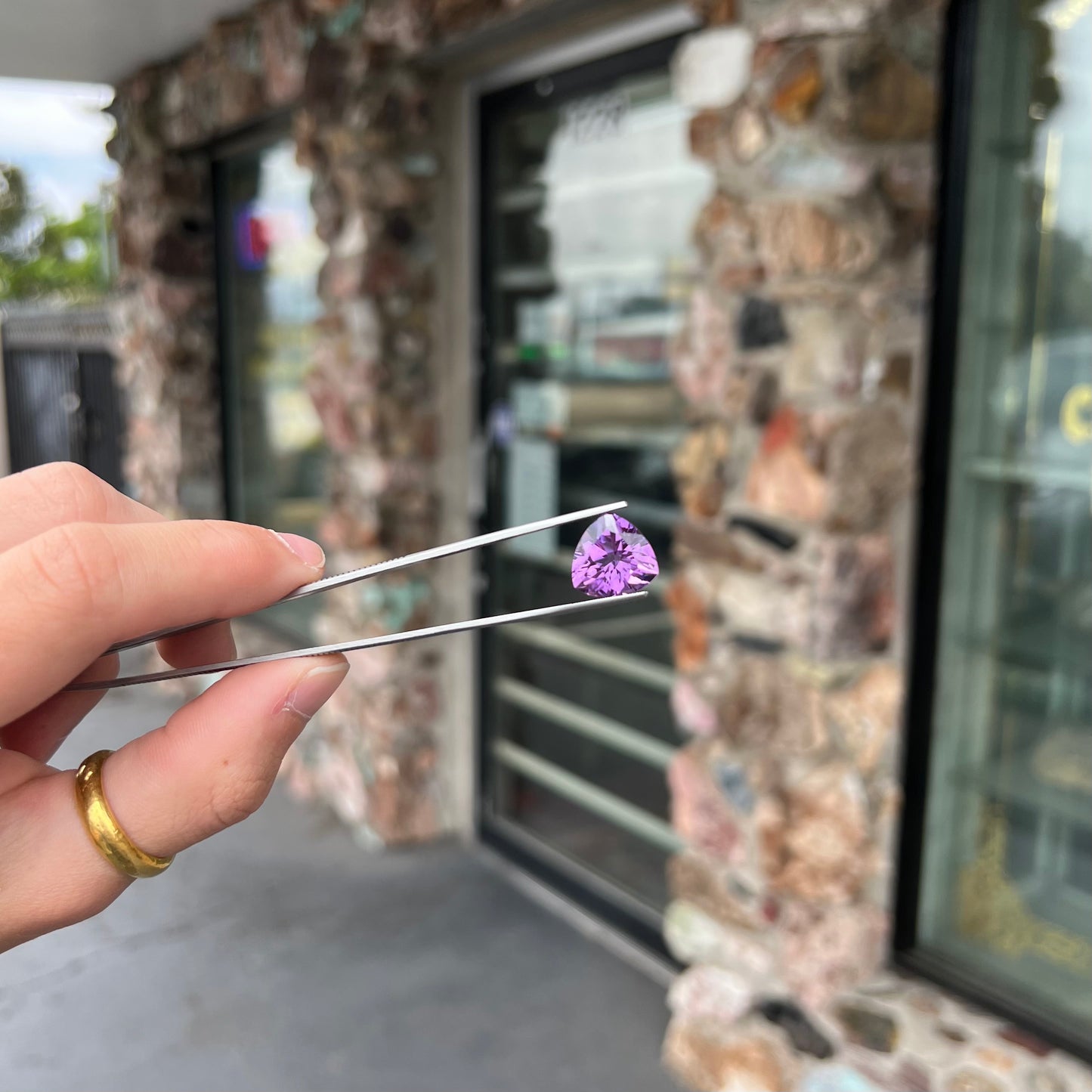 A loose, faceted trillion cut amethyst gemstone.