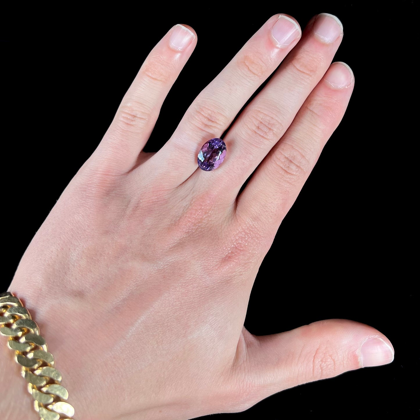 A faceted oval cut amethyst gemstone. The stone is a light purple color.
