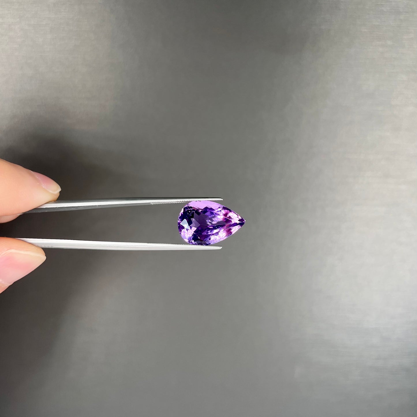 A loose, pear shaped amethyst gemstone. The stone is a medium purple color.