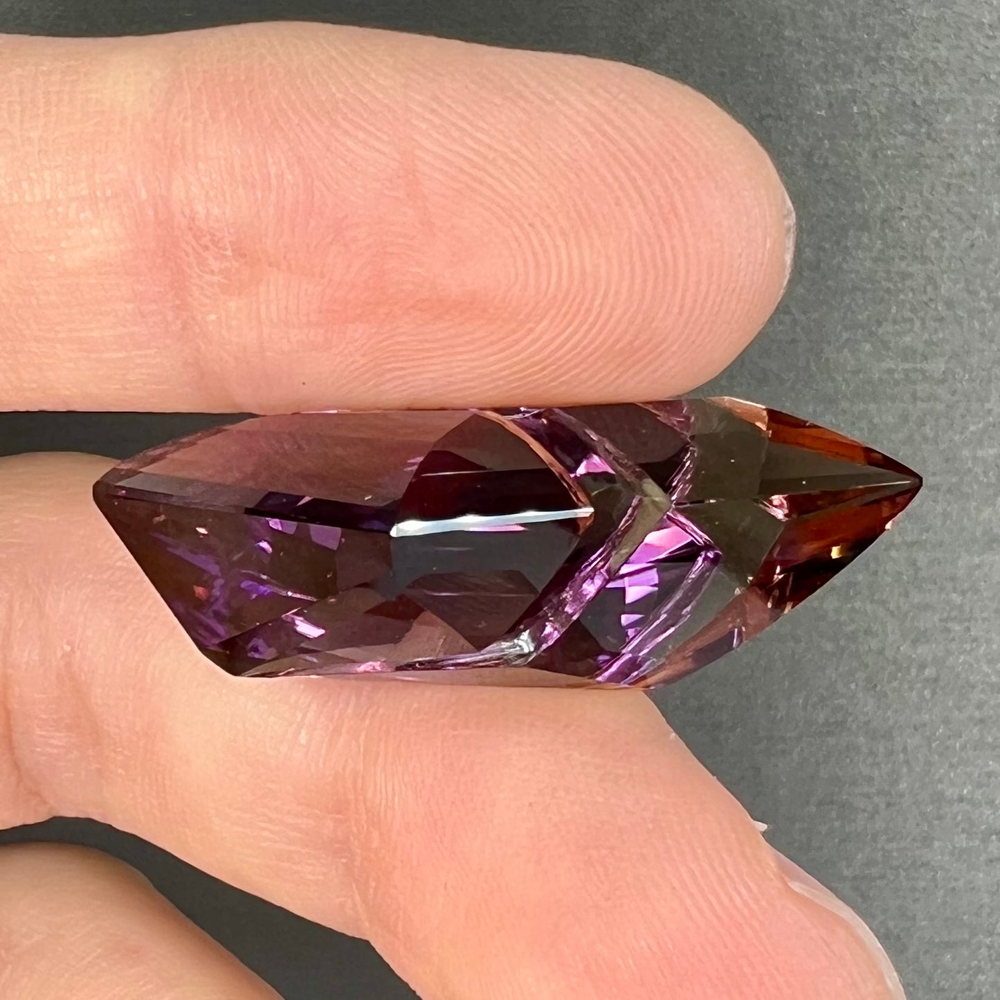 A loose, faceted fantasy cut ametrine gemstone cut by famous carver, Arthur Lee Anderson.