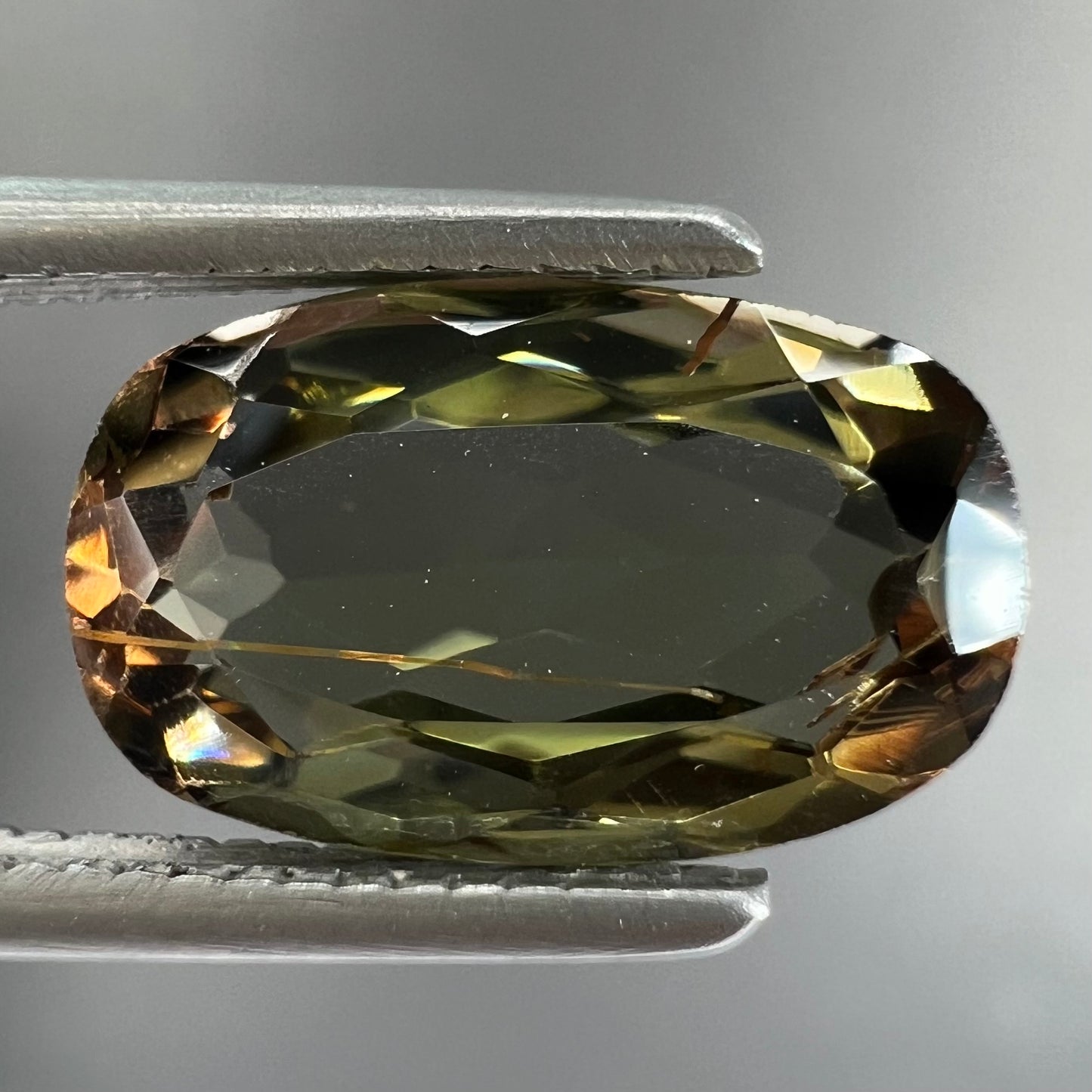 A modified oval cut andalusite gemstone. The stone has eye-visible rutile inclusions.