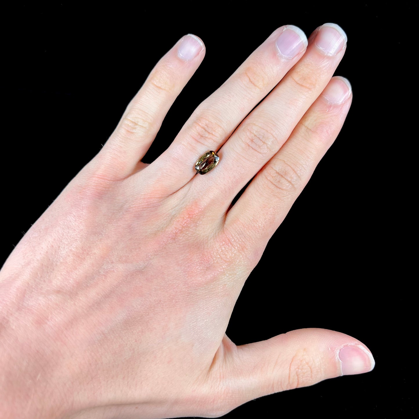A modified oval cut andalusite gemstone. The stone has eye-visible rutile inclusions.