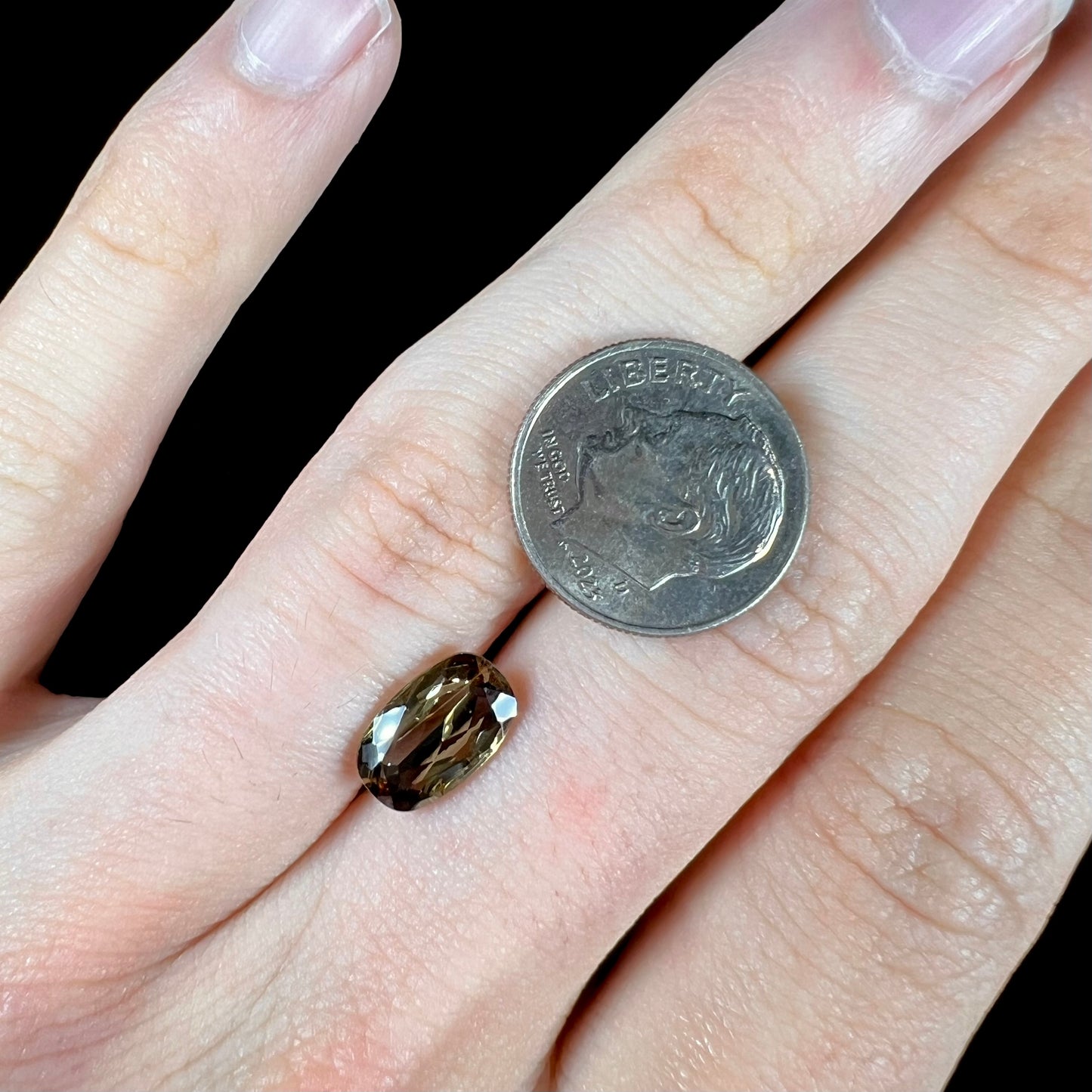 A modified oval cut andalusite gemstone. The stone has eye-visible rutile inclusions.