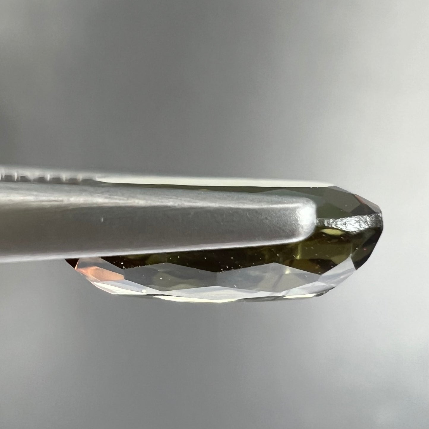 A modified oval cut andalusite gemstone. The stone has eye-visible rutile inclusions.