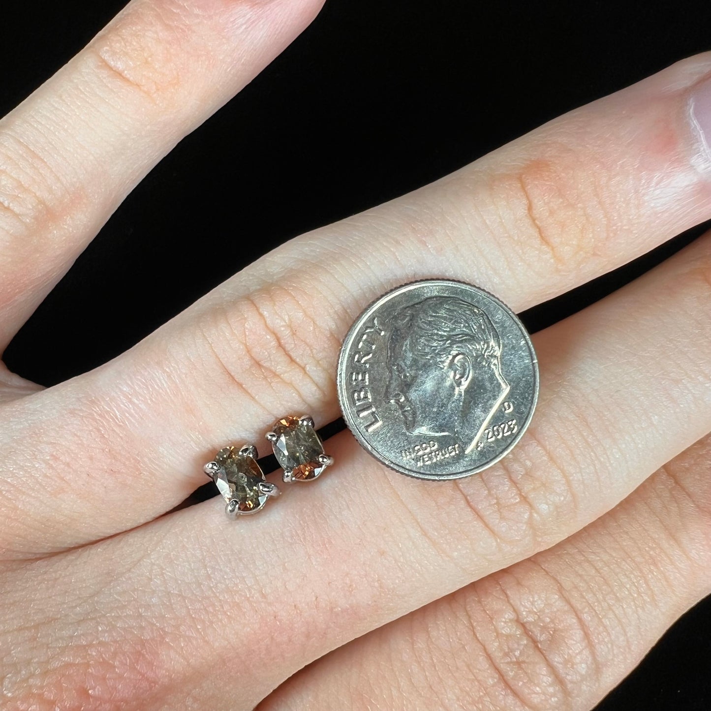 A pair of sterling silver stud earrings prong set with oval cut andalusite stones.