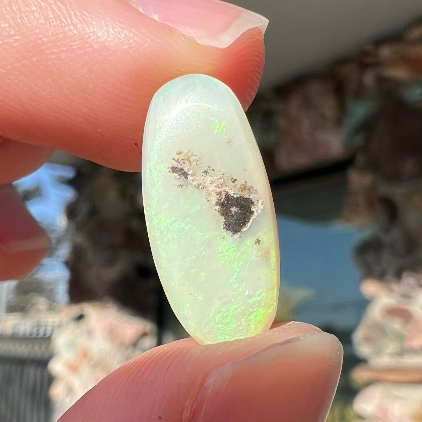 An oval cabochon cut opal from Andamooka, Australia. The opal has green and orange color play.