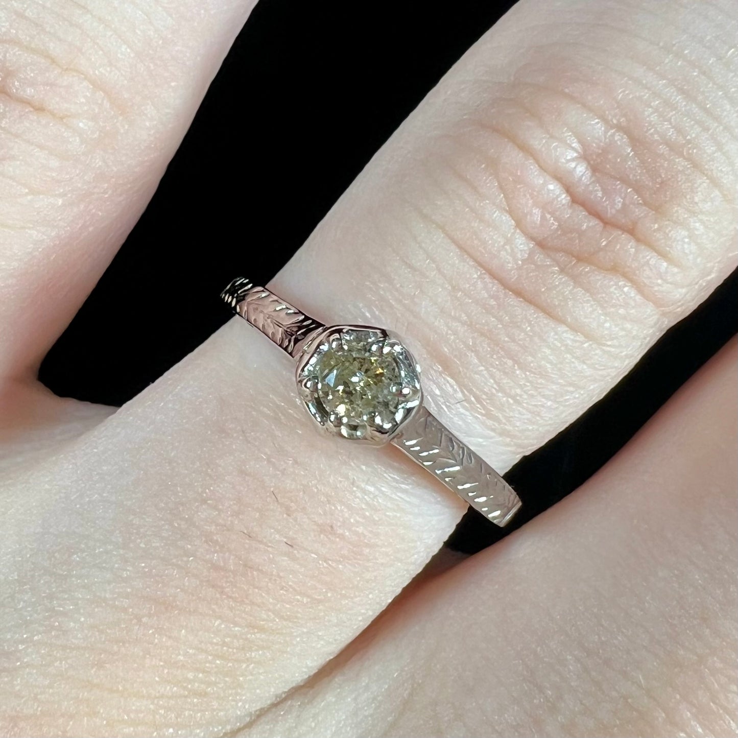 An Art Deco style 18 karat white gold diamond solitaire ring. The ring has scroll work on the side of the shank.