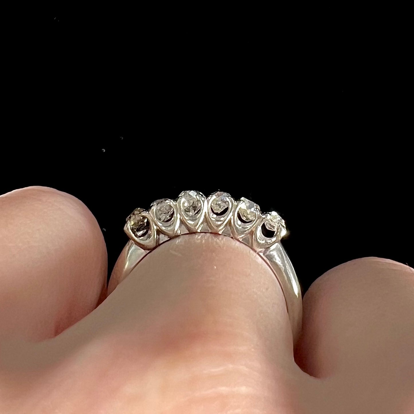 An antique white gold diamond wedding band set with six old mine cut natural diamonds.