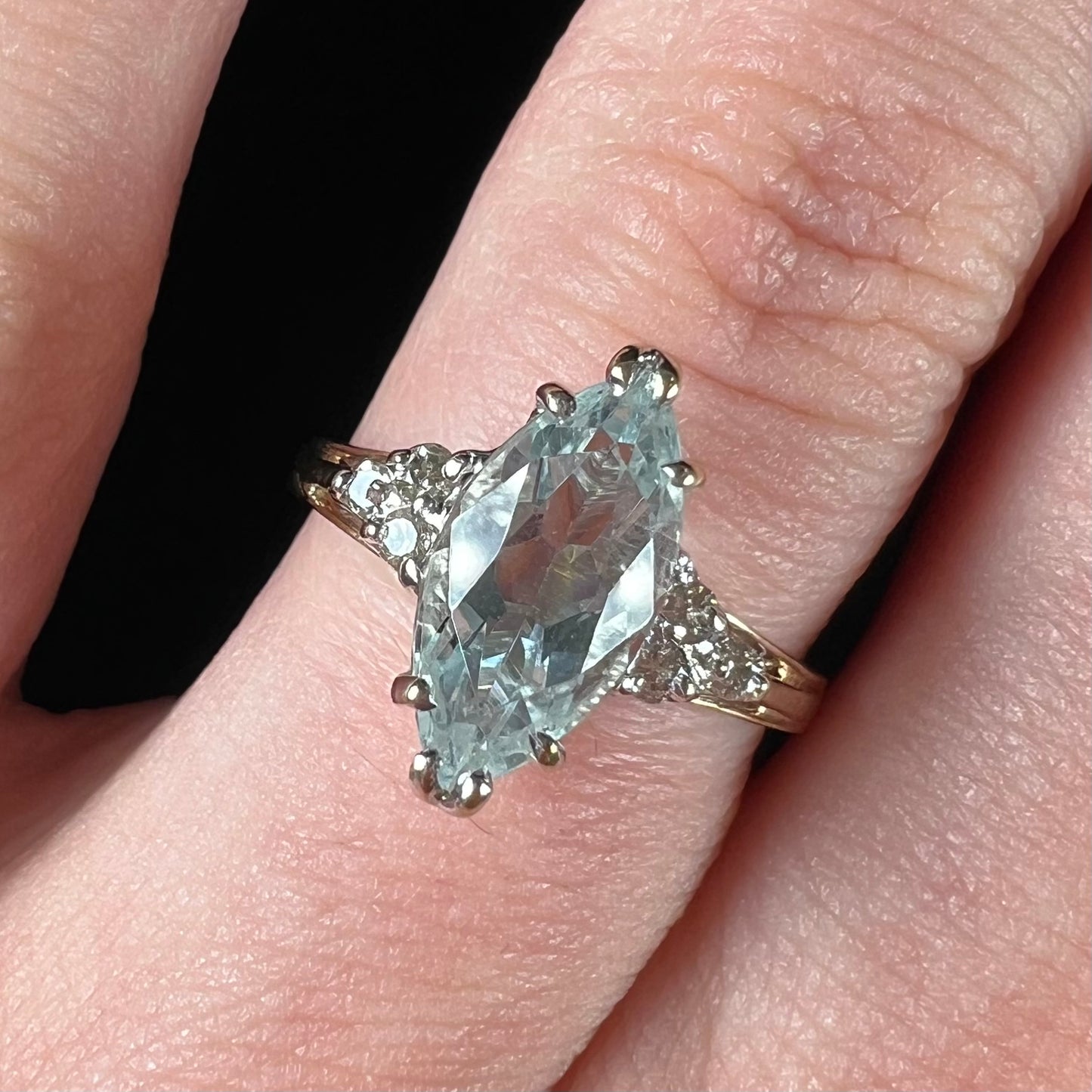 A ladies' ring set with a marquise cut aquamarine and round accent diamonds.