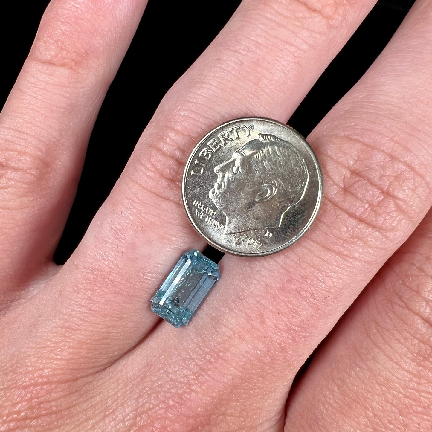 A loose, faceted emerald cut aquamarine stone. The stone is icy blue in color, indicative of Vietnamese origin.