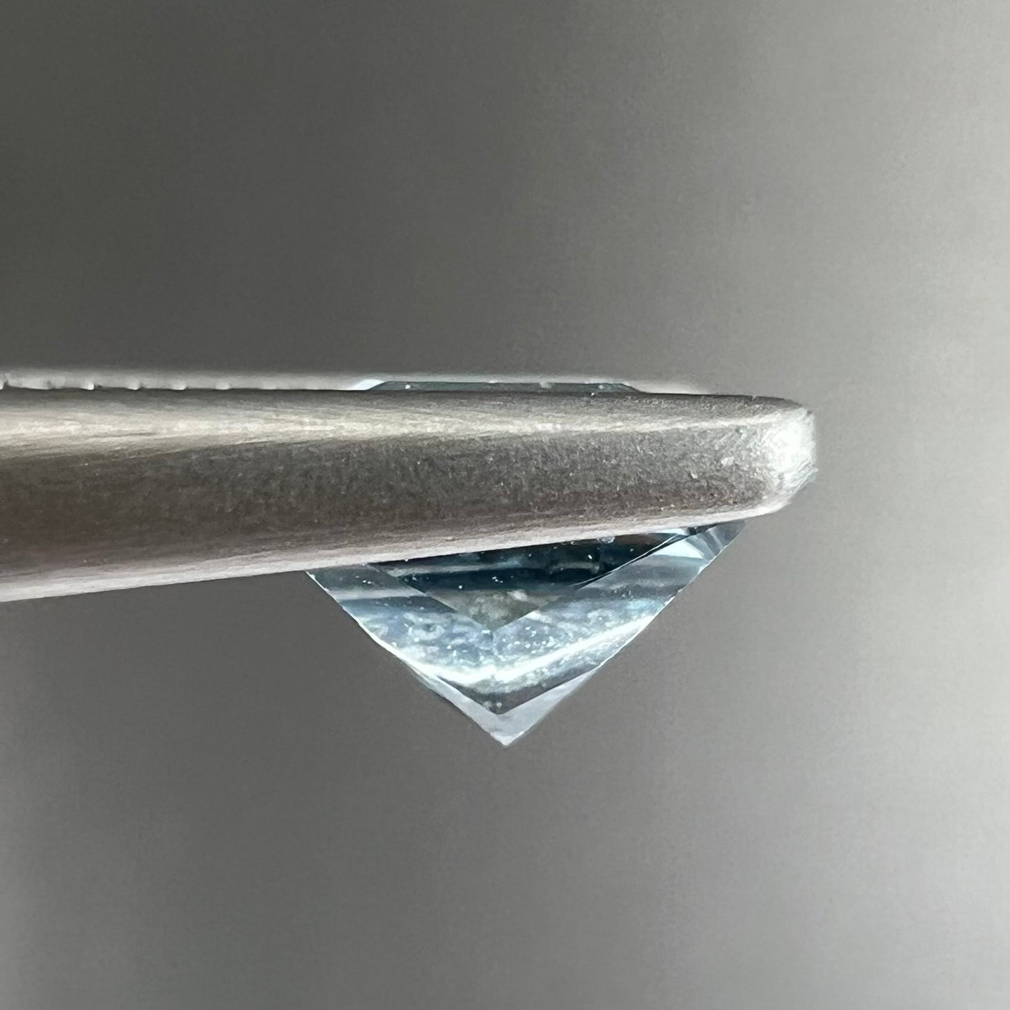 A loose, princess cut aquamarine gemstone. The stone is a light blue color.