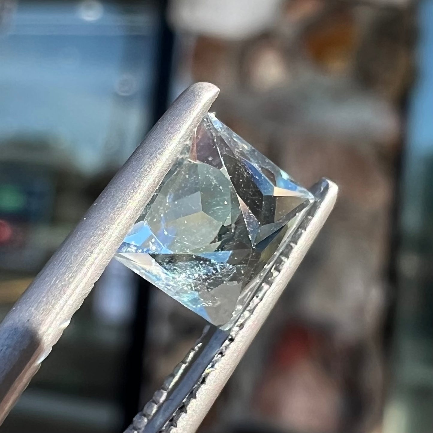 A loose, princess cut aquamarine gemstone. The stone is a light blue color.