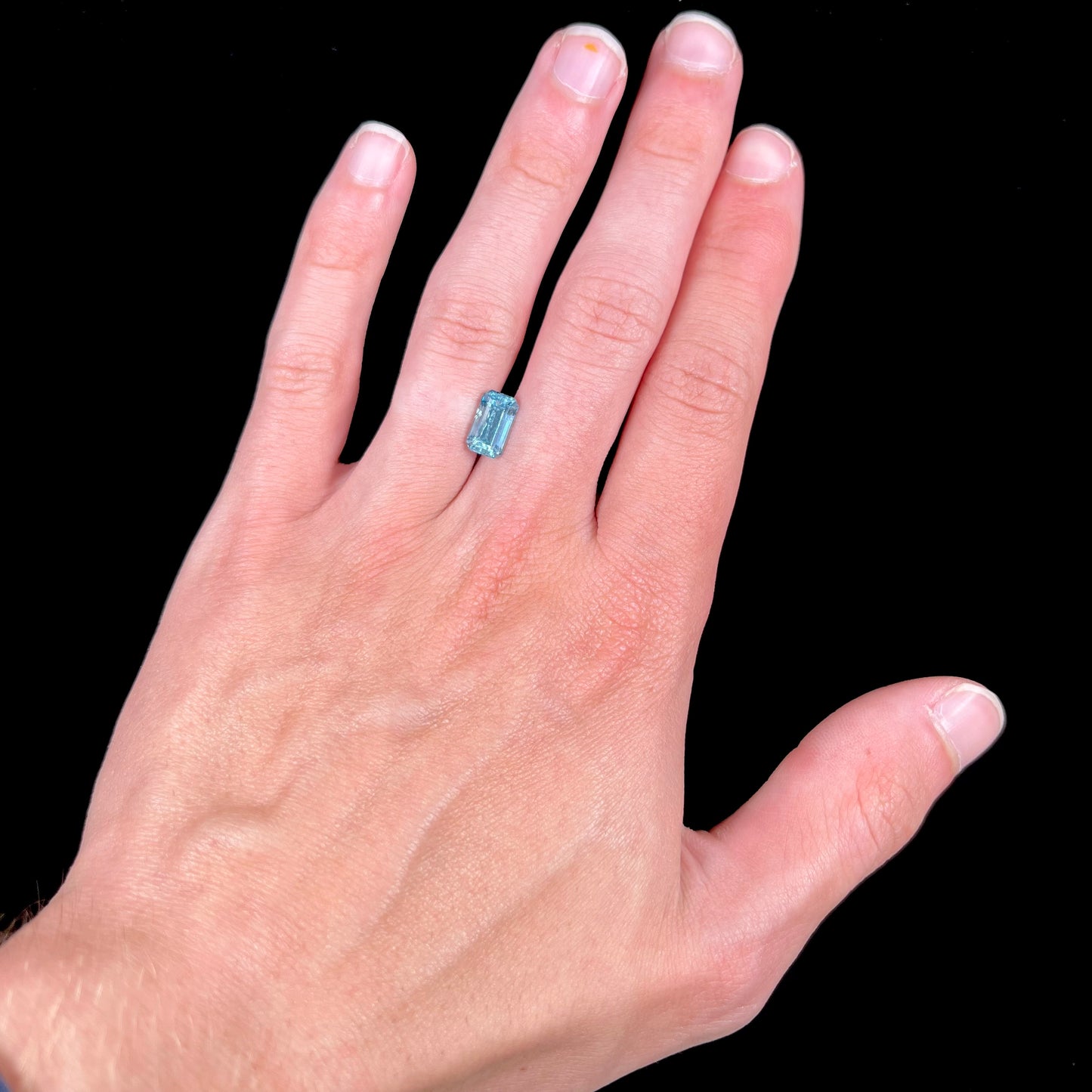A loose, faceted emerald cut aquamarine stone. The stone is icy blue in color, indicative of Vietnamese origin.