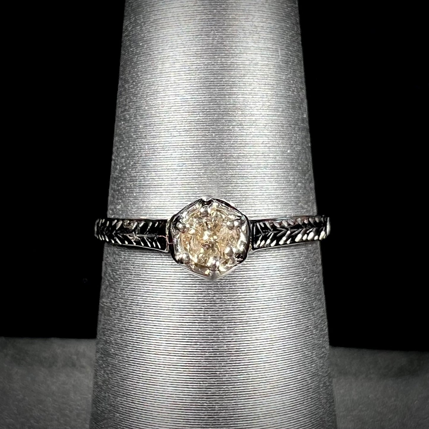 An Art Deco style 18 karat white gold diamond solitaire ring. The ring has scroll work on the side of the shank.