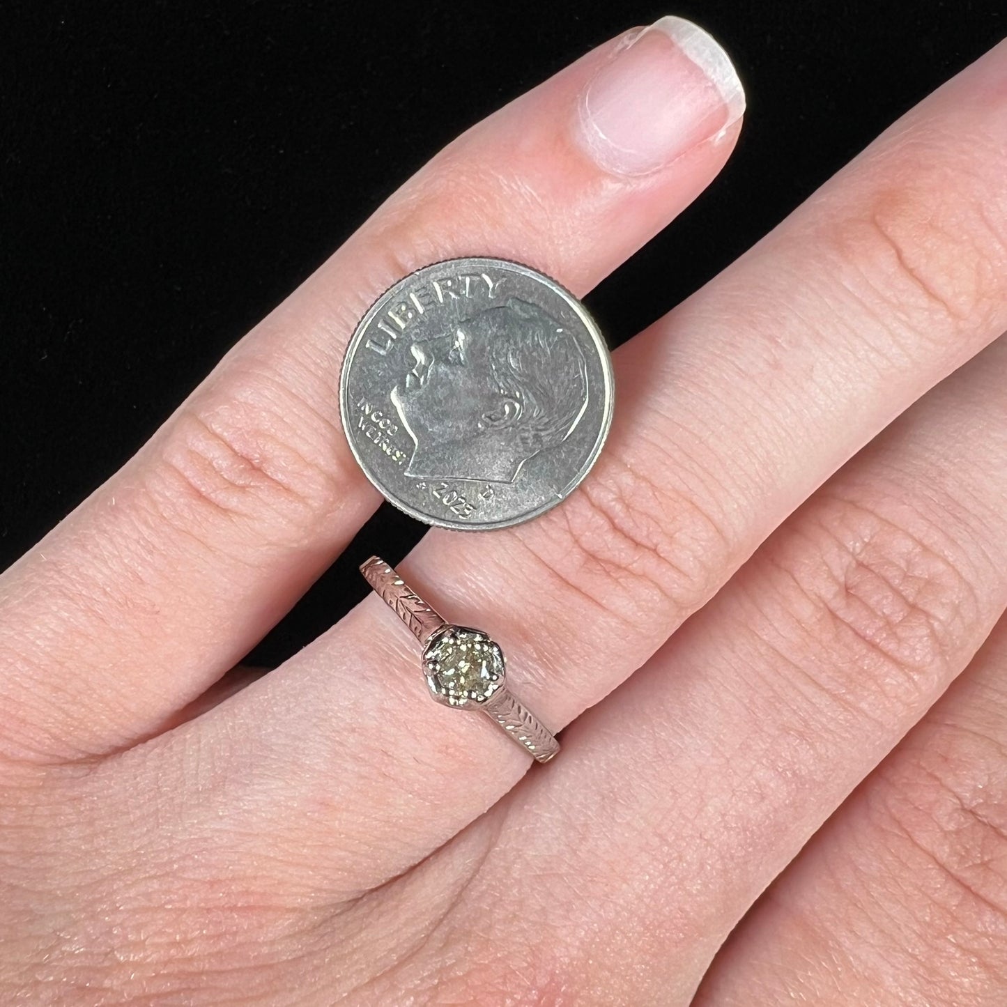 An Art Deco style 18 karat white gold diamond solitaire ring. The ring has scroll work on the side of the shank.