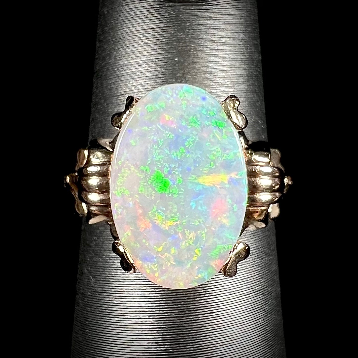 A ladies' Art Deco style natural opal solitaire ring in yellow gold. The opal is oval cut.