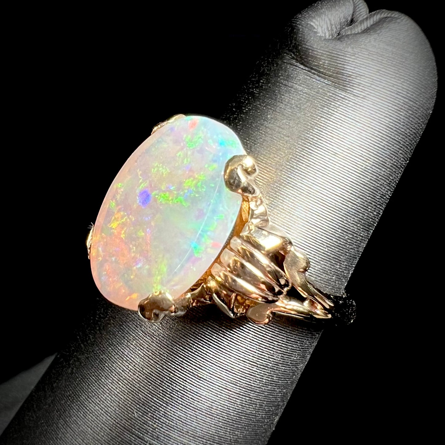 A ladies' Art Deco style natural opal solitaire ring in yellow gold. The opal is oval cut.