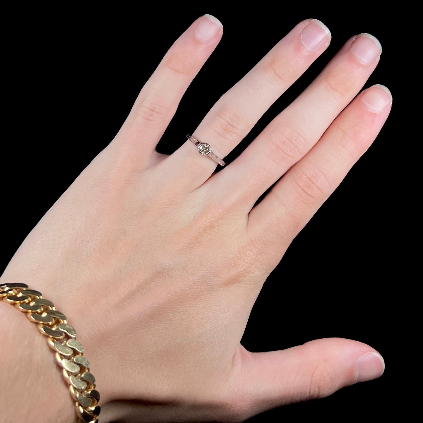 An Art Deco style 18 karat white gold diamond solitaire ring. The ring has scroll work on the side of the shank.