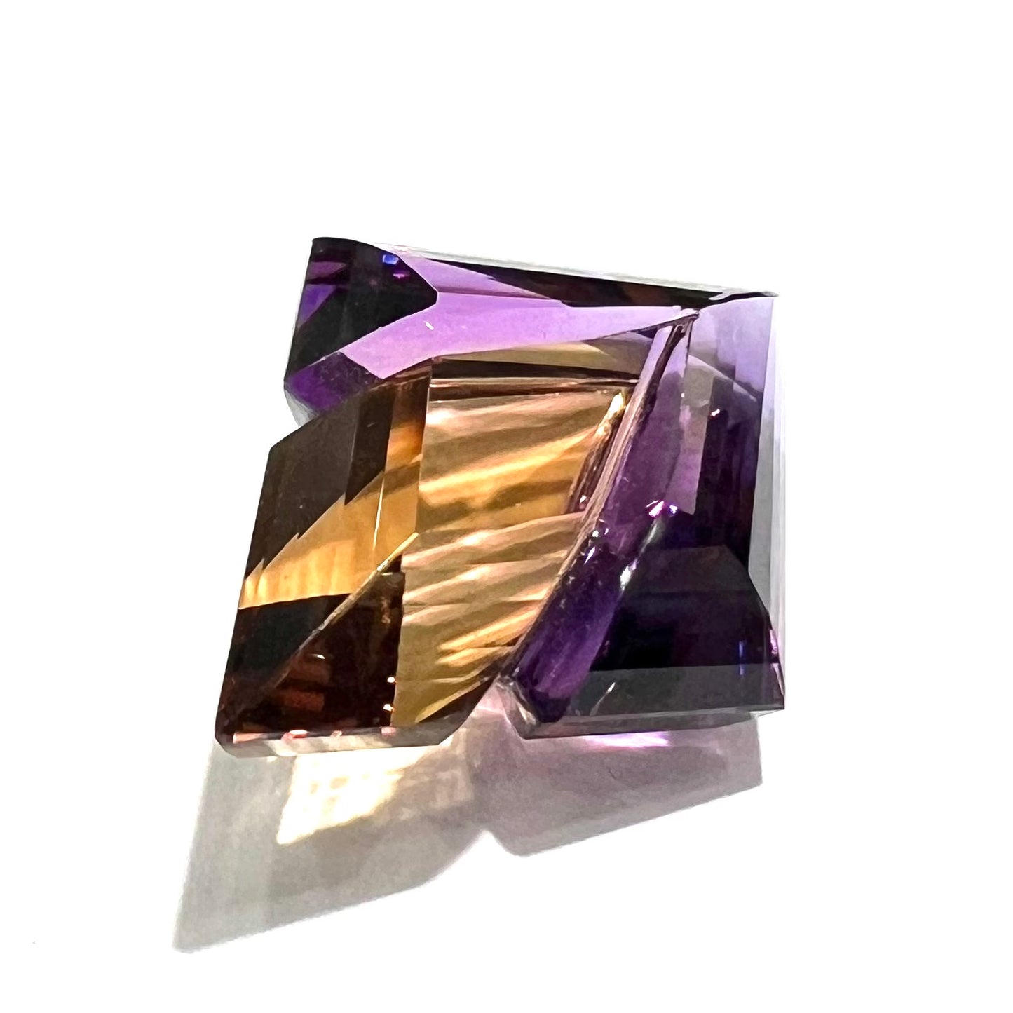 A loose, faceted fantasy cut ametrine gemstone cut by famous carver, Arthur Lee Anderson.