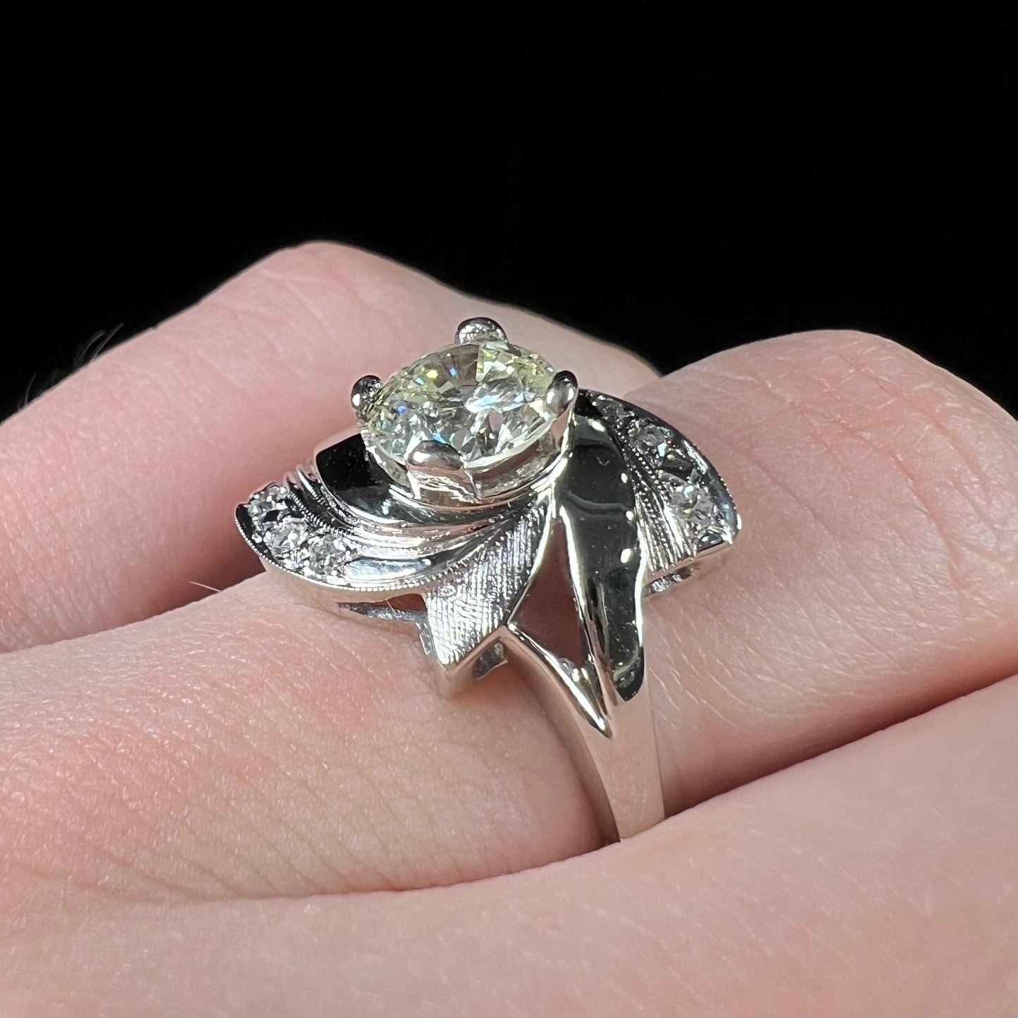 A vintage, Art Nouveau style diamond engagment ring. The ring is white gold with a yellowish, M colored, 1.24 carat diamond.