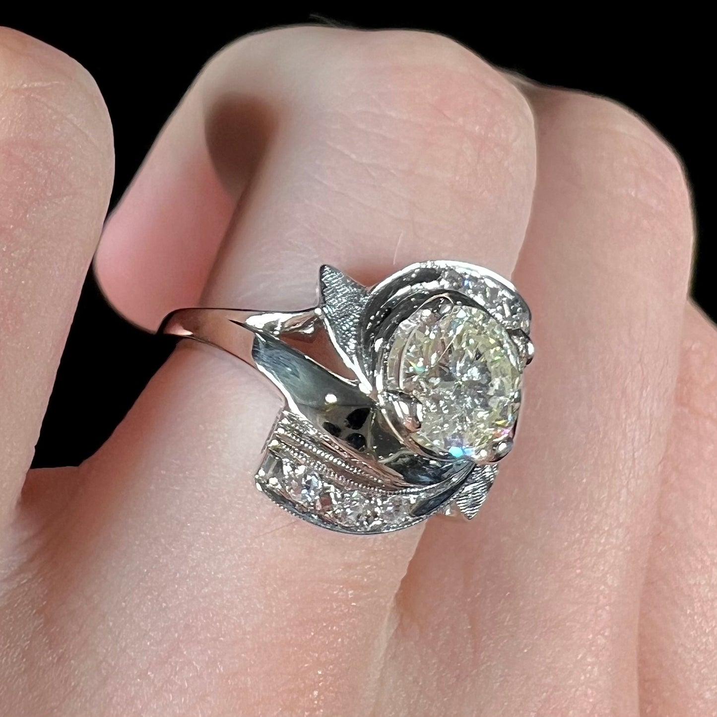 A vintage, Art Nouveau style diamond engagment ring. The ring is white gold with a yellowish, M colored, 1.24 carat diamond.