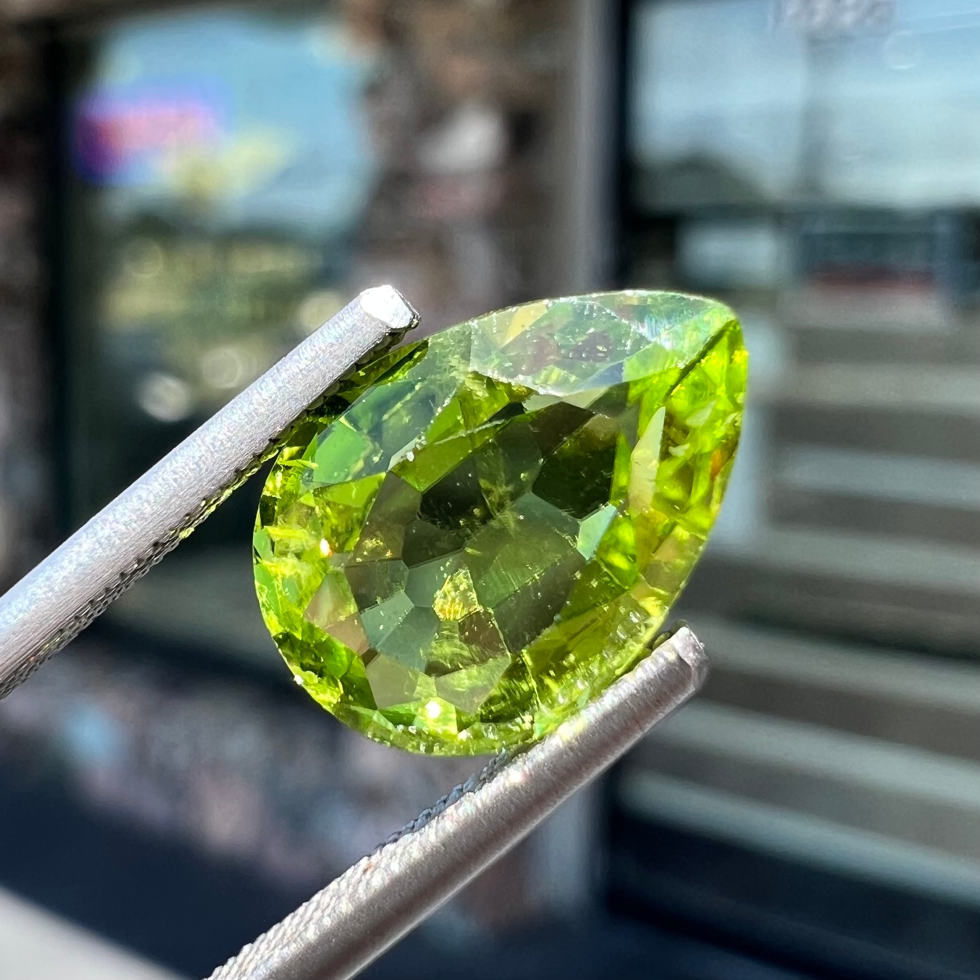 A loose, yellow green, pear shaped peridot gemstone.