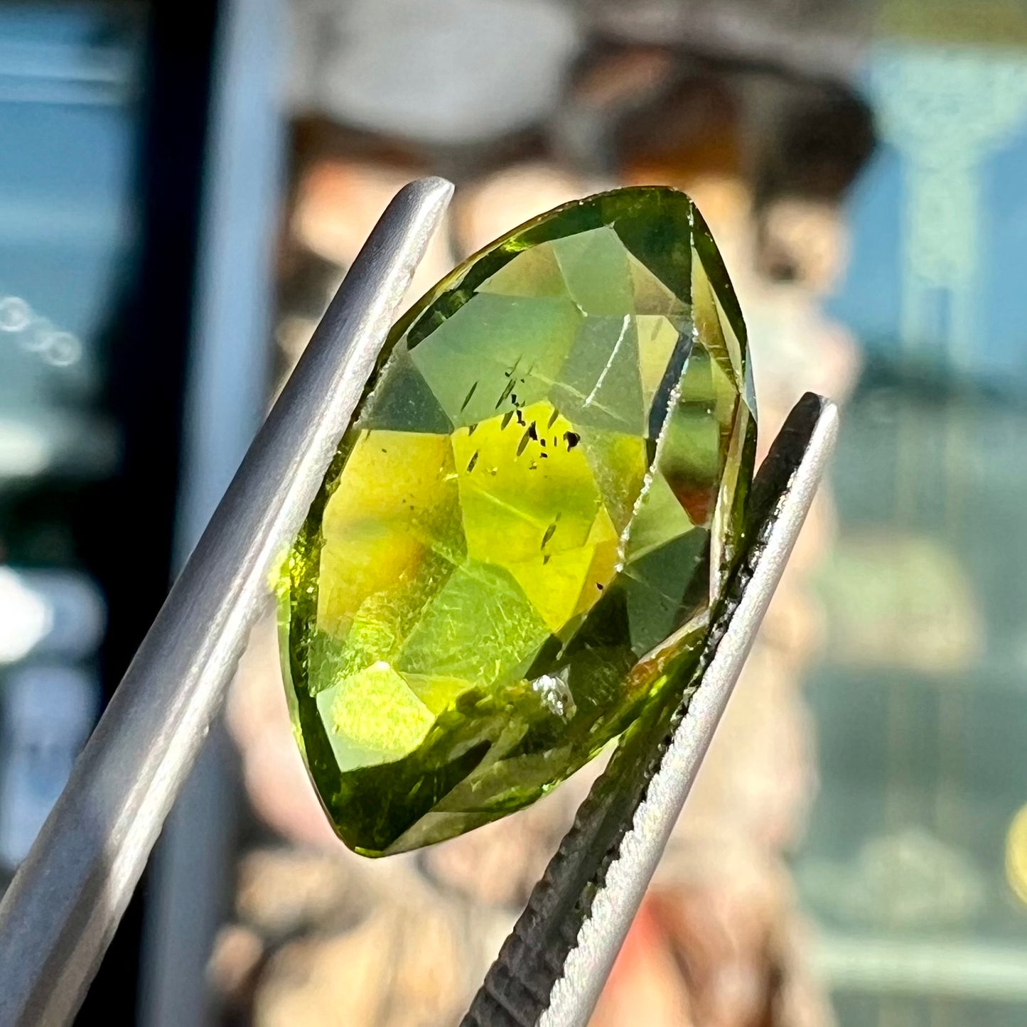 A loose, marquise cut peridot gemstone. The stone is an olive green color.