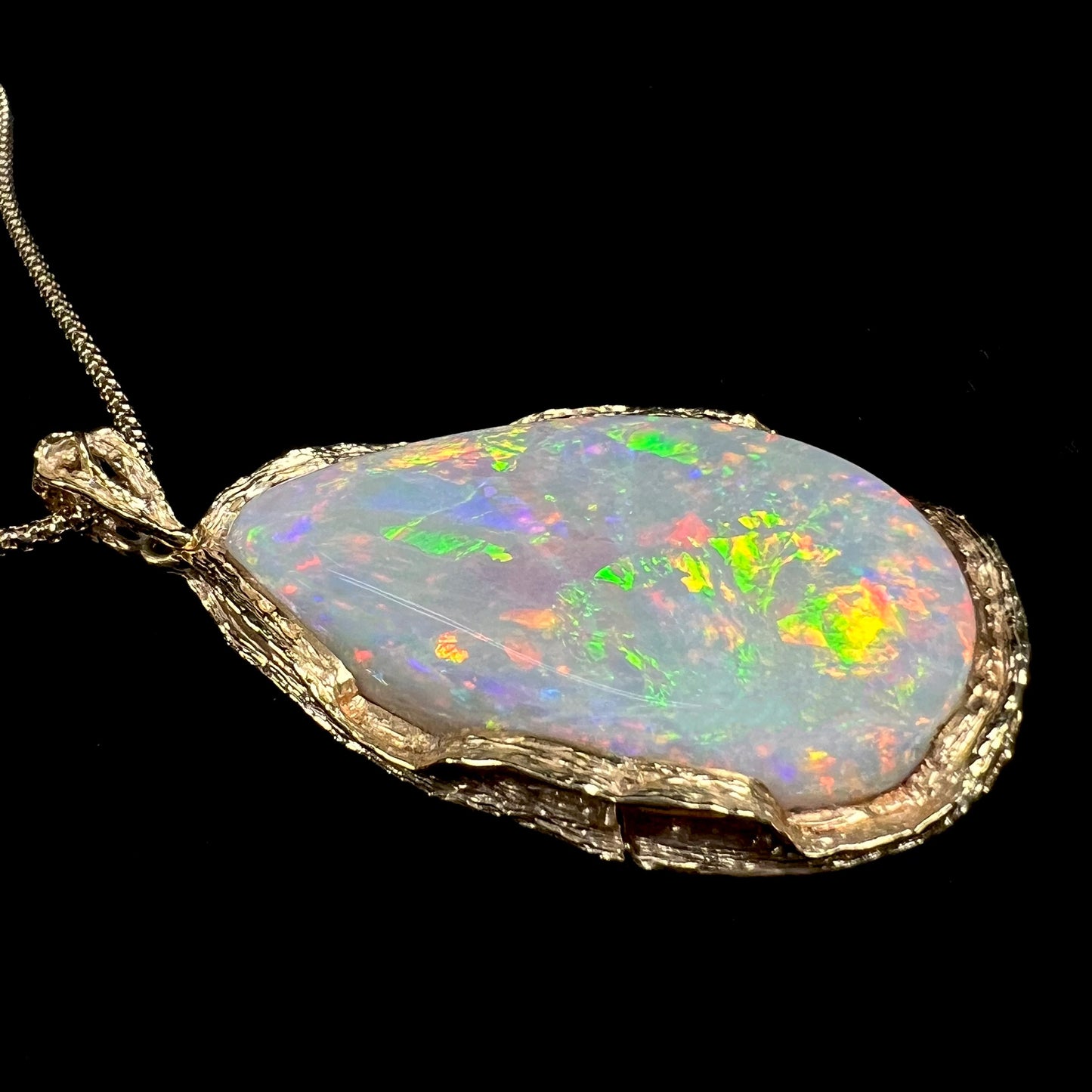A ladies' natural, pear shaped, gray base Australian opal pendant set in 18 karat yellow gold.