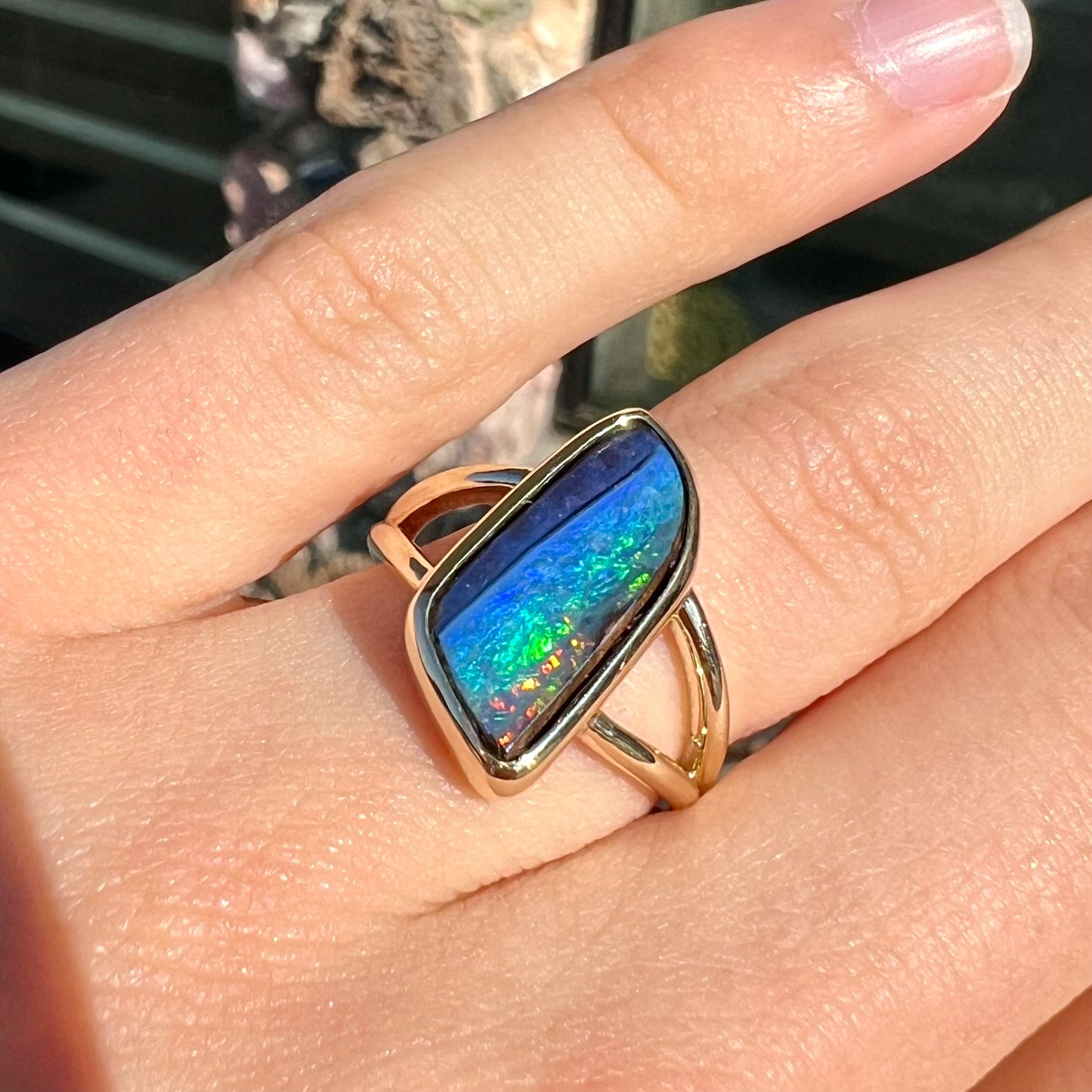 A ladies' split shank gold ring bezel set with a natural, Australian black boulder opal.