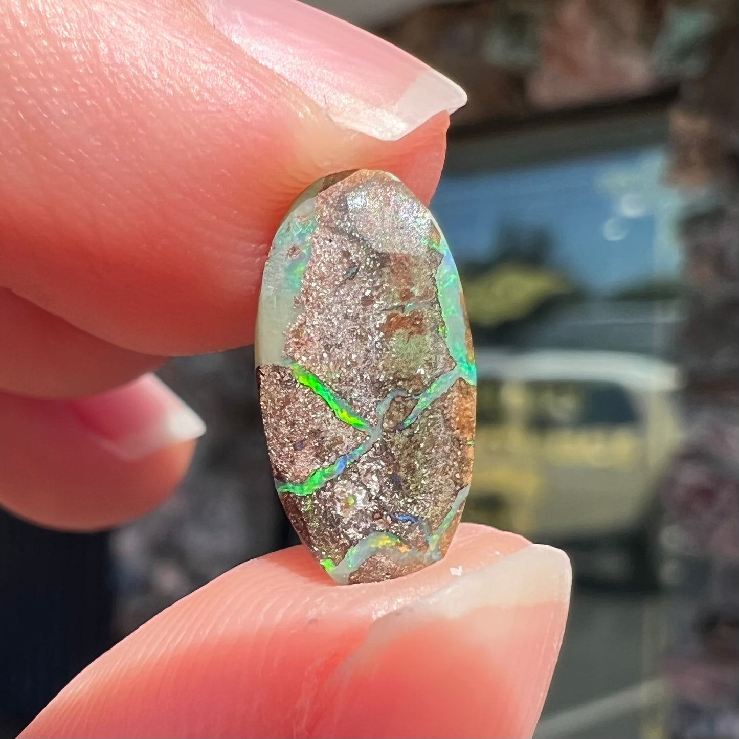 A loose, oval cabochon cut Koroit boulder opal stone. The opal has a bright green color.