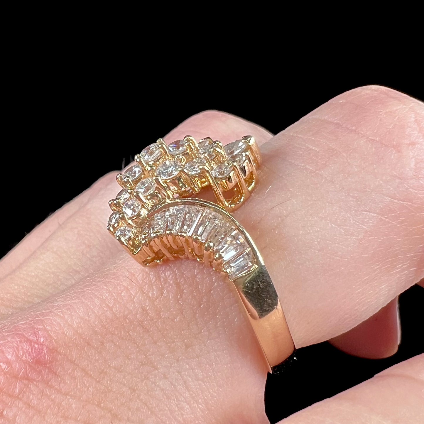 A yellow gold diamond cluster ring set with round, marquise, and baguette cut diamonds.