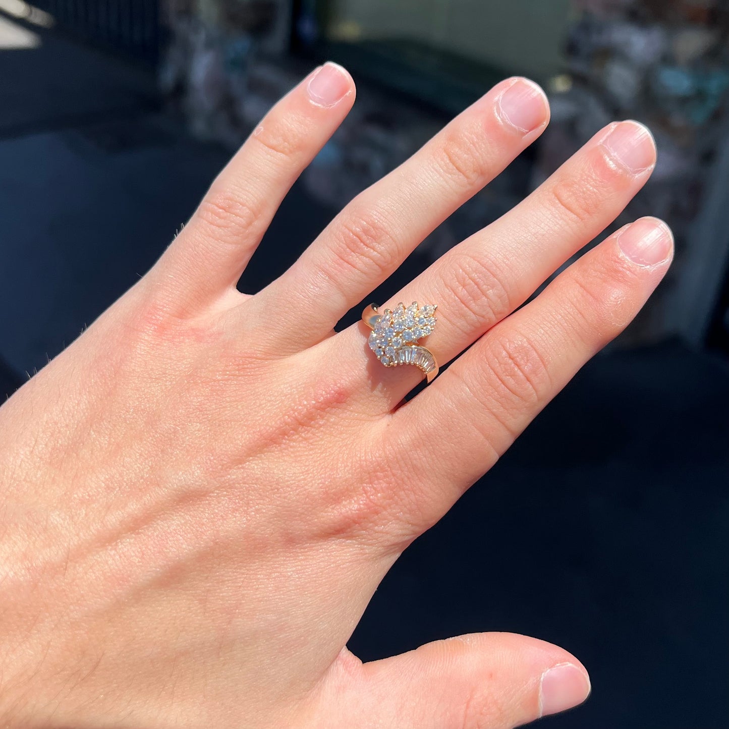 A yellow gold diamond cluster ring set with round, marquise, and baguette cut diamonds.