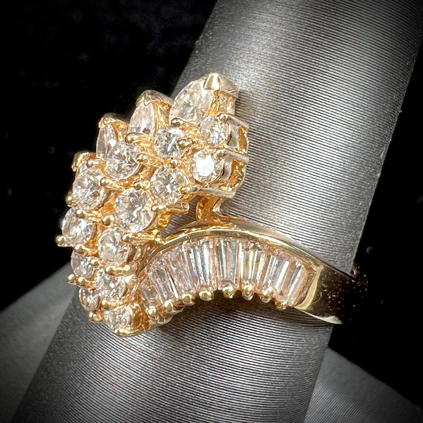 A yellow gold diamond cluster ring set with round, marquise, and baguette cut diamonds.