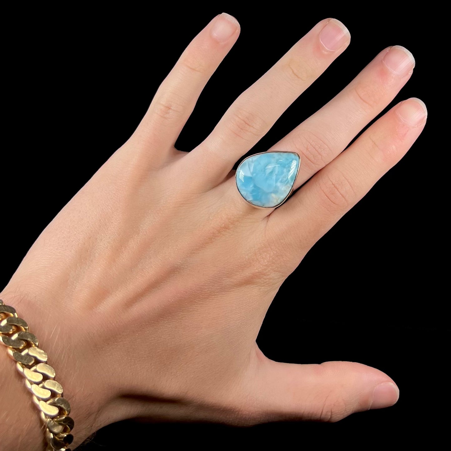 A ladies' large, pear shaped larimar solitaire ring in sterling silver. The larimar stone measures an inch long.