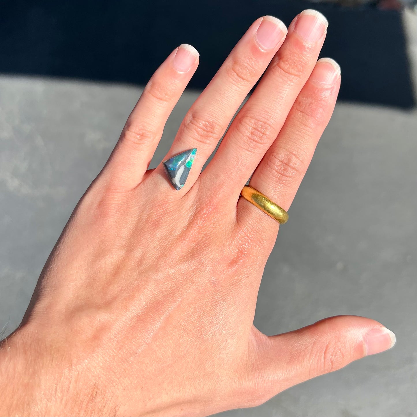 A loose, triangle shaped black opal stone from Lightning Ridge, Australia. The opal has different colors of black and semi-black opal potch.